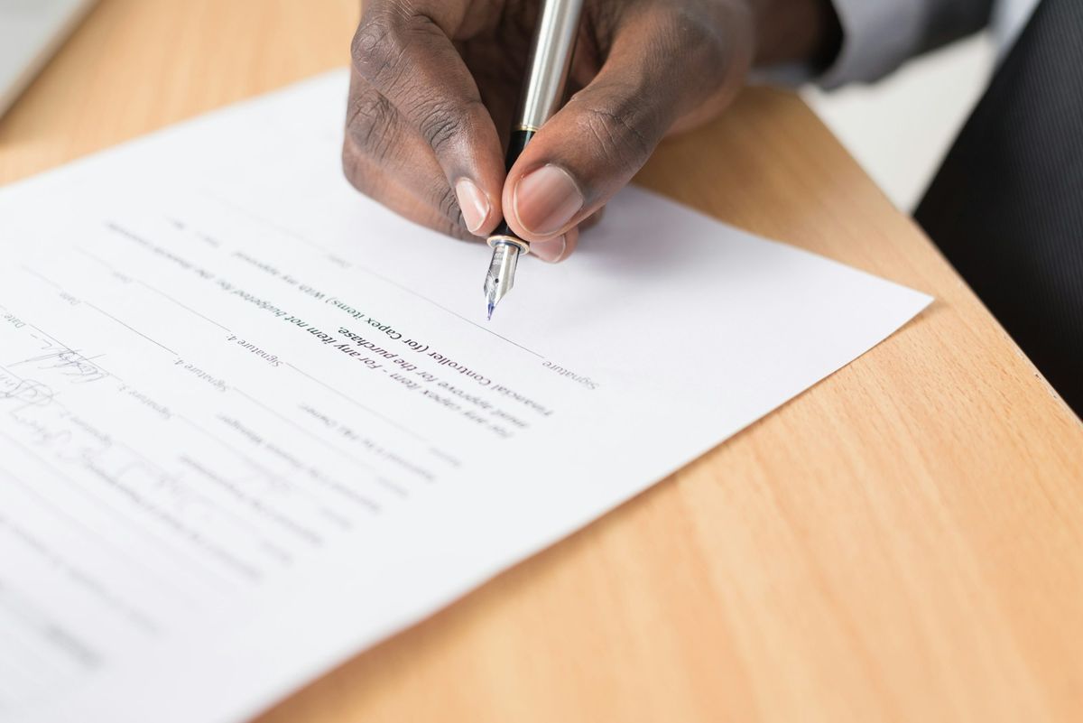 Person filling out an official document by hand