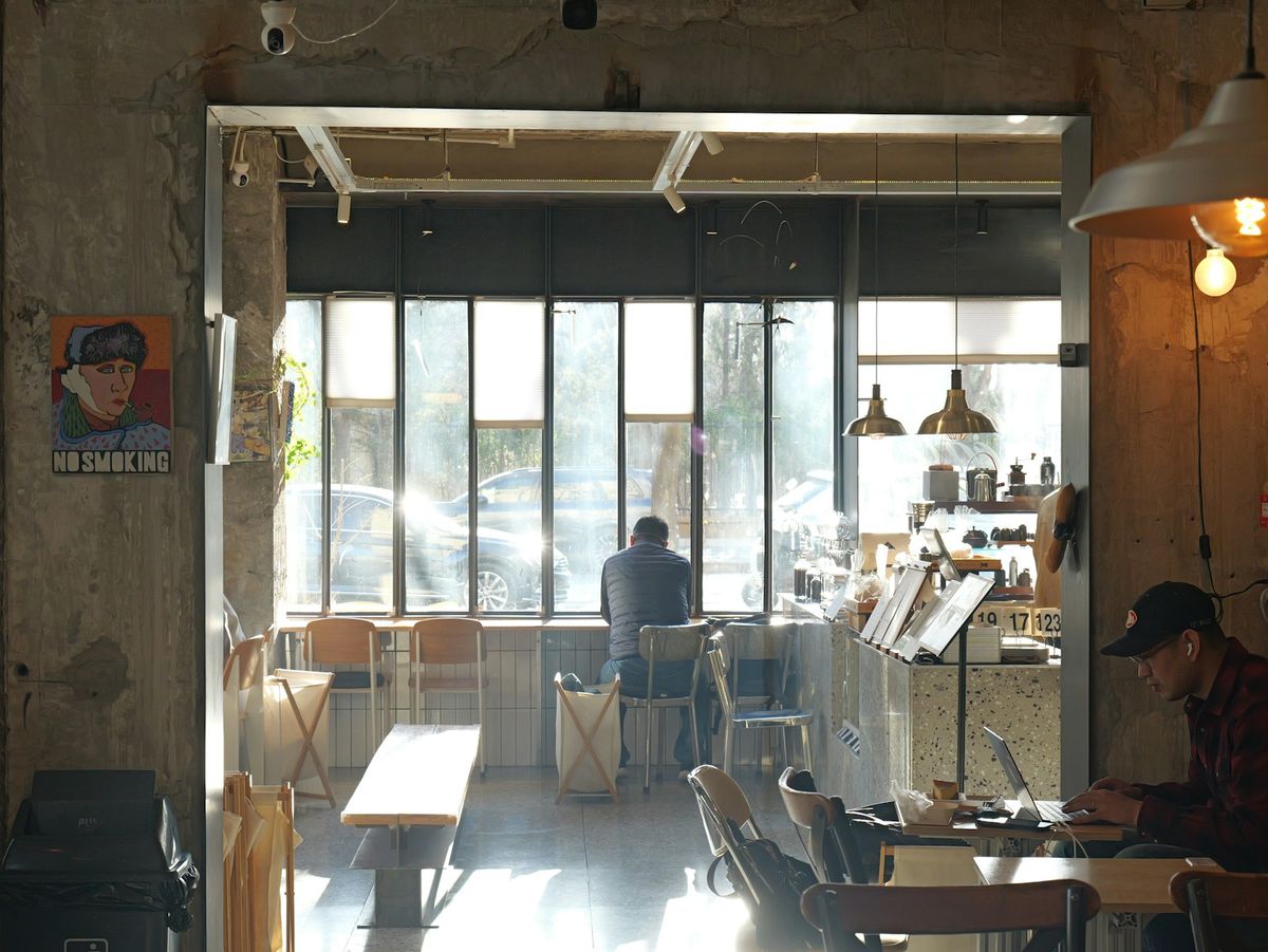A person working on a laptop in a sunlit cafe