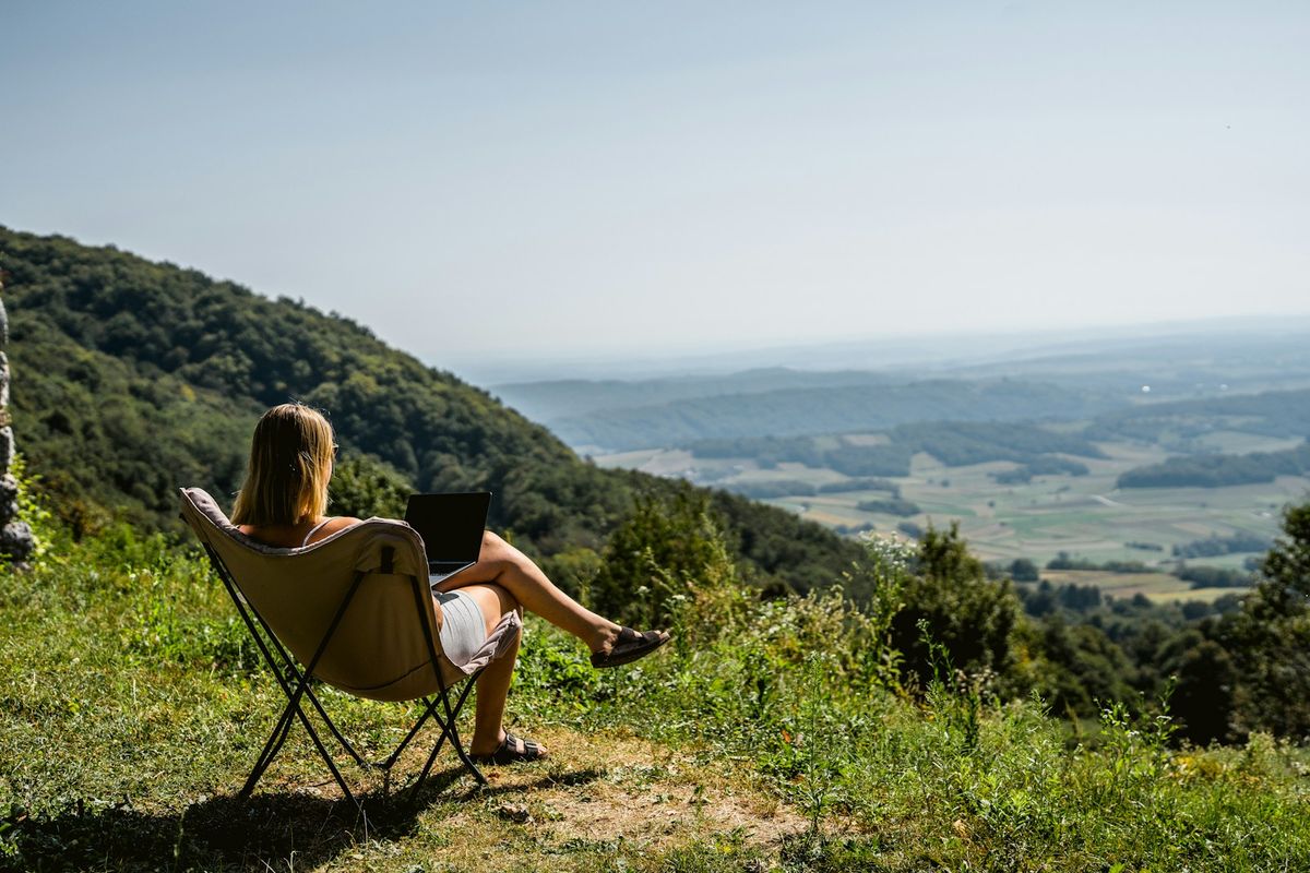 Woman working on laptop on a scenic mountain overlook
