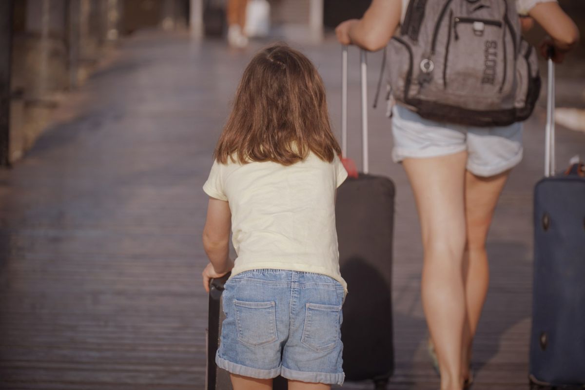 Parent and child walking with luggage while travelling