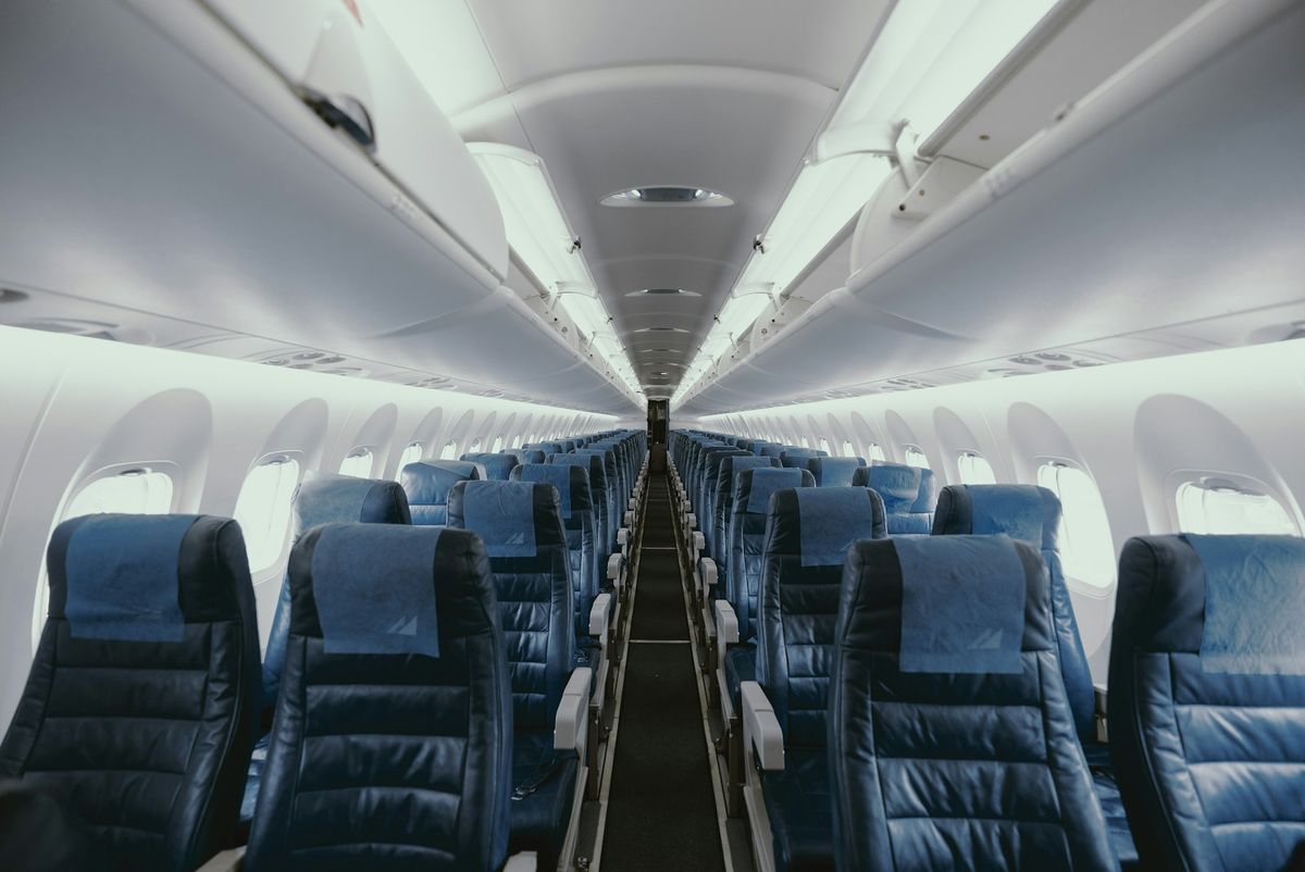 Blue-toned airplane cabin interior with rows of seats
