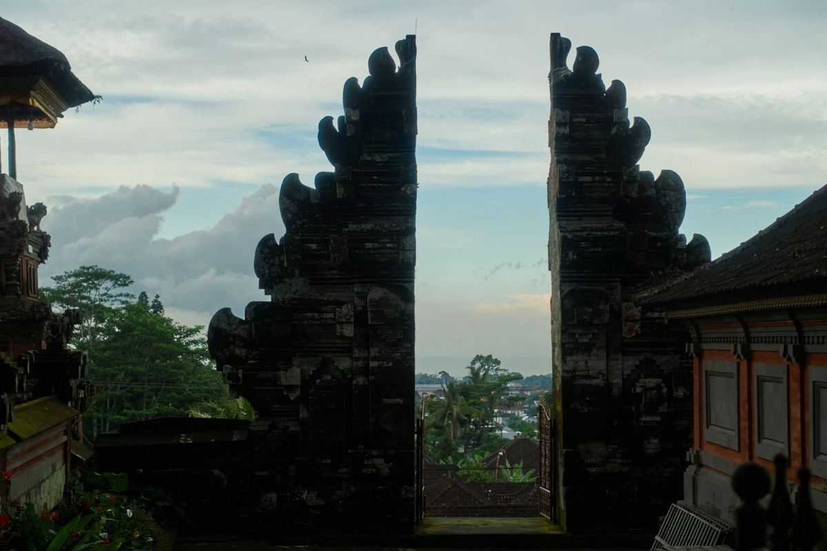 Ornate Balinese stone gate opening to scenic landscape