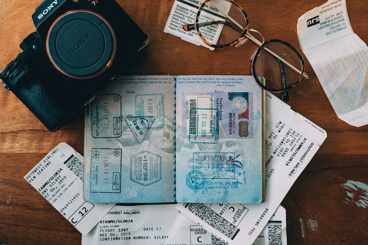 Open passport with visa stamps next to a camera and boarding passes