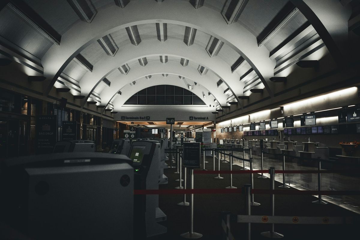 Empty airport terminal with rows of check-in counters at night