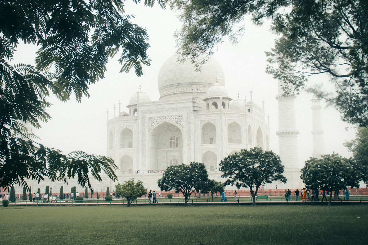 Taj Mahal mausoleum in misty weather viewed through trees