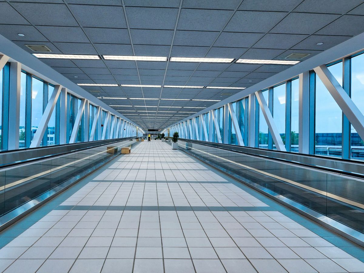 Modern airport corridor with glass partitions and moving walkway