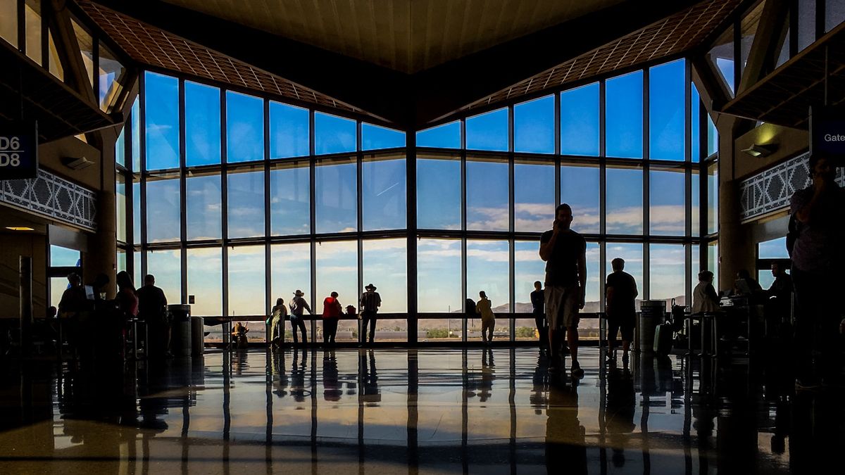 Travelers in a bright airport terminal with large windows