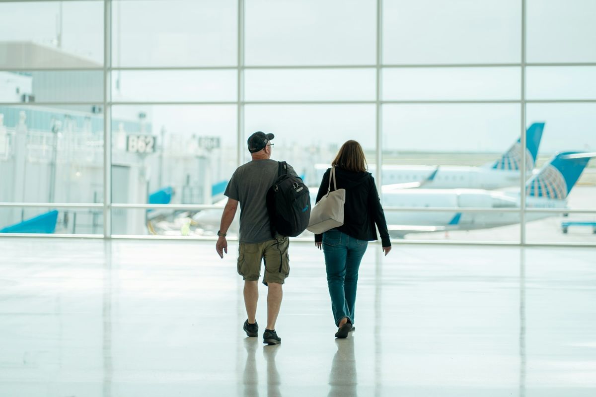 Couple walking through airport terminal with baggage