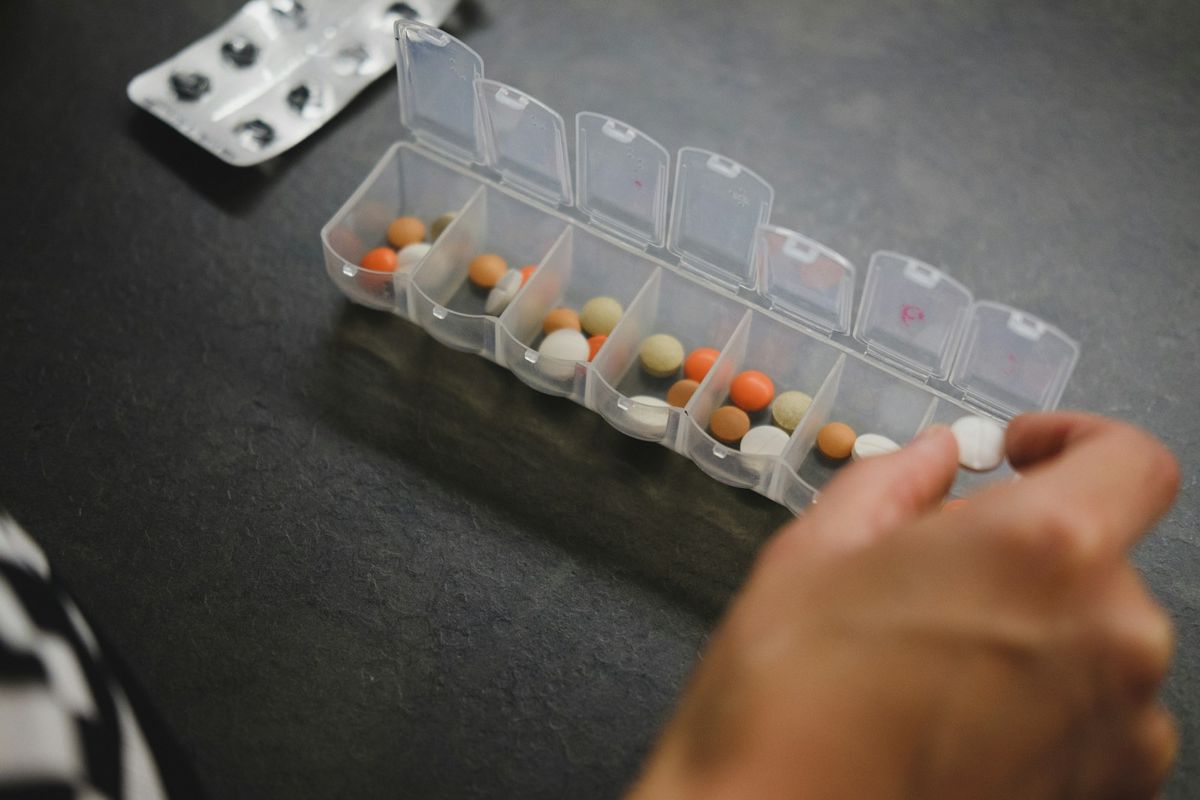 Person selecting medication from a pill organizer
