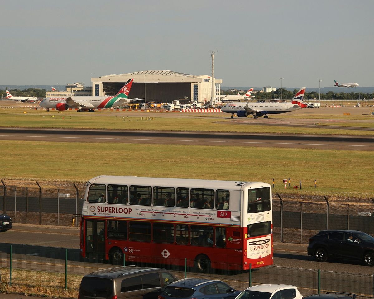 Double-decker bus on road with airplanes at airport