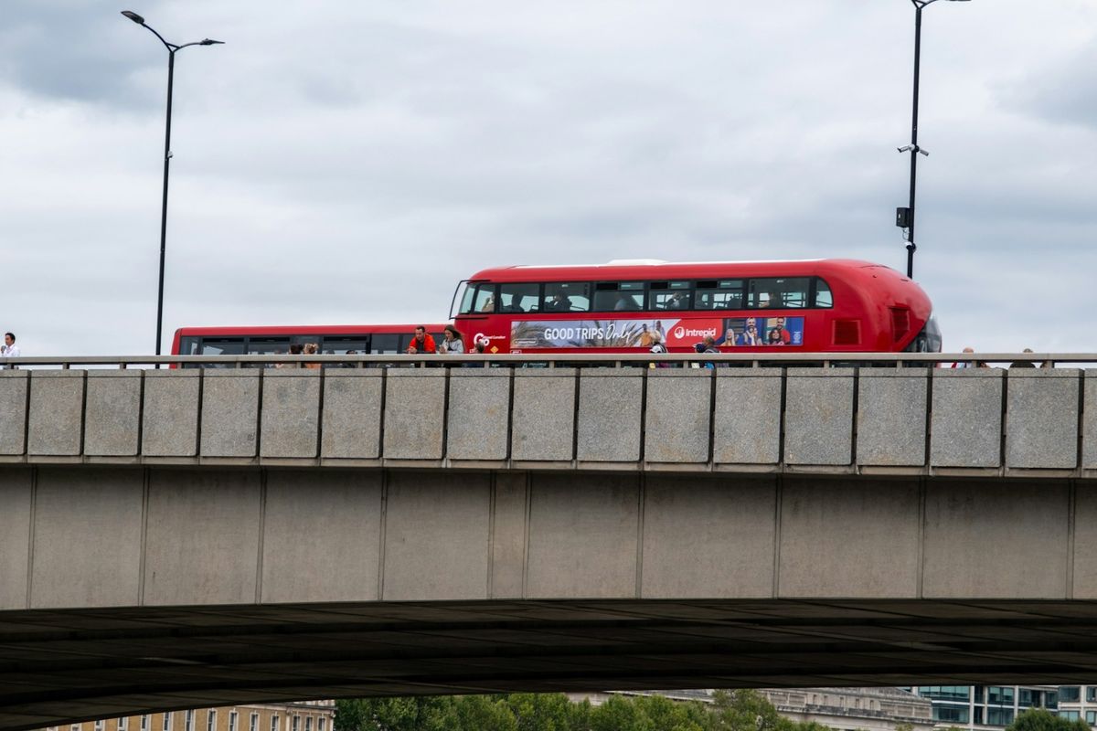 Red double decker bus crossing a bridge in London near an airport