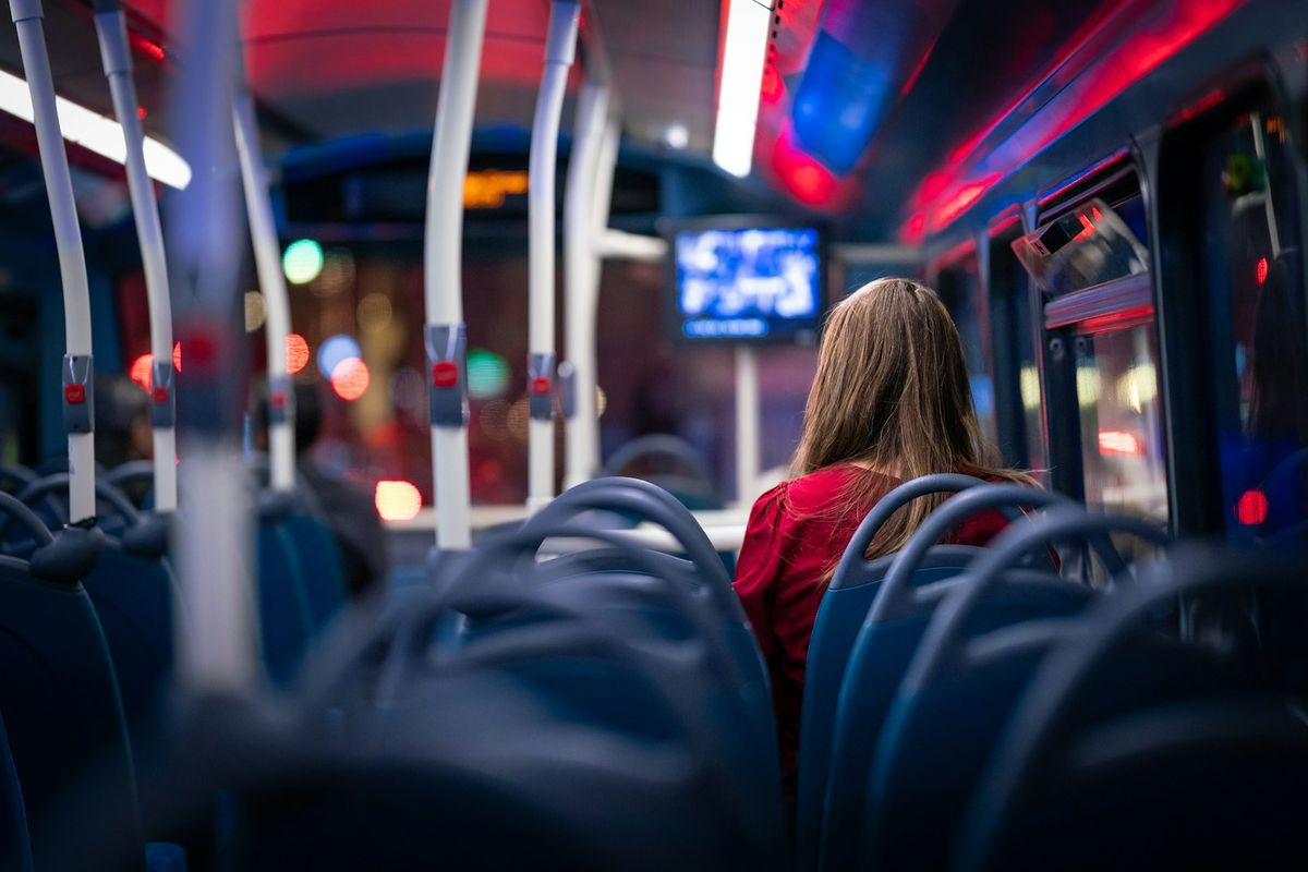 Solitary passenger seated alone on a coach bus during a night journey