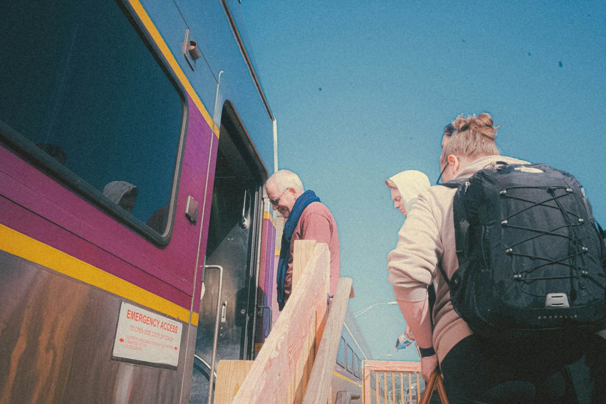 Group of travelers boarding a bus on a sunny day