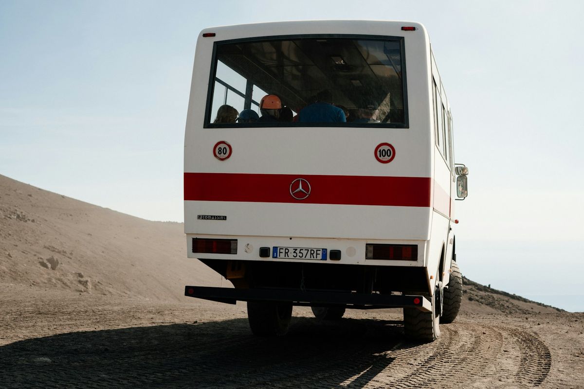 White coach bus traveling on a dusty rural road