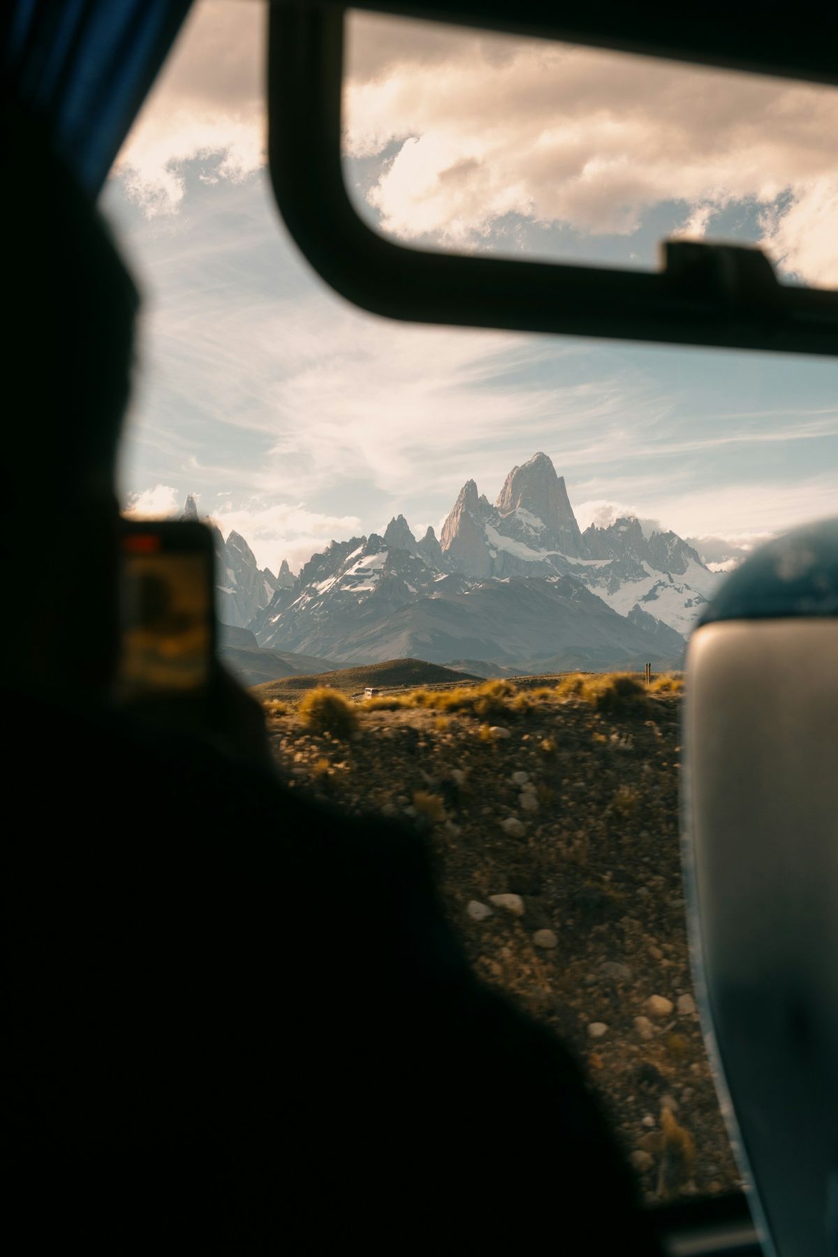 Snow-capped Patagonian mountains framed through a bus window