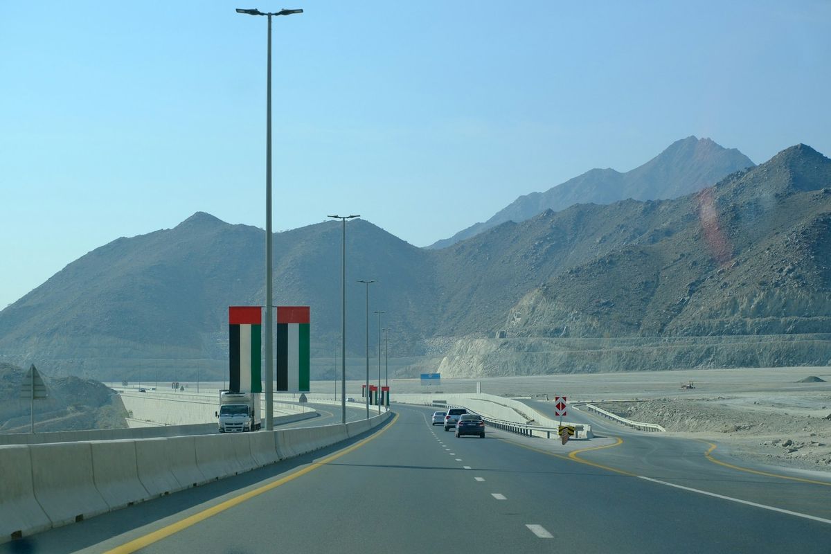 Desert highway with UAE flags and mountains Middle East