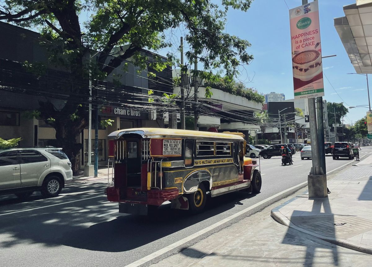A colourful jeepney drives down a sunny street in the Philippines