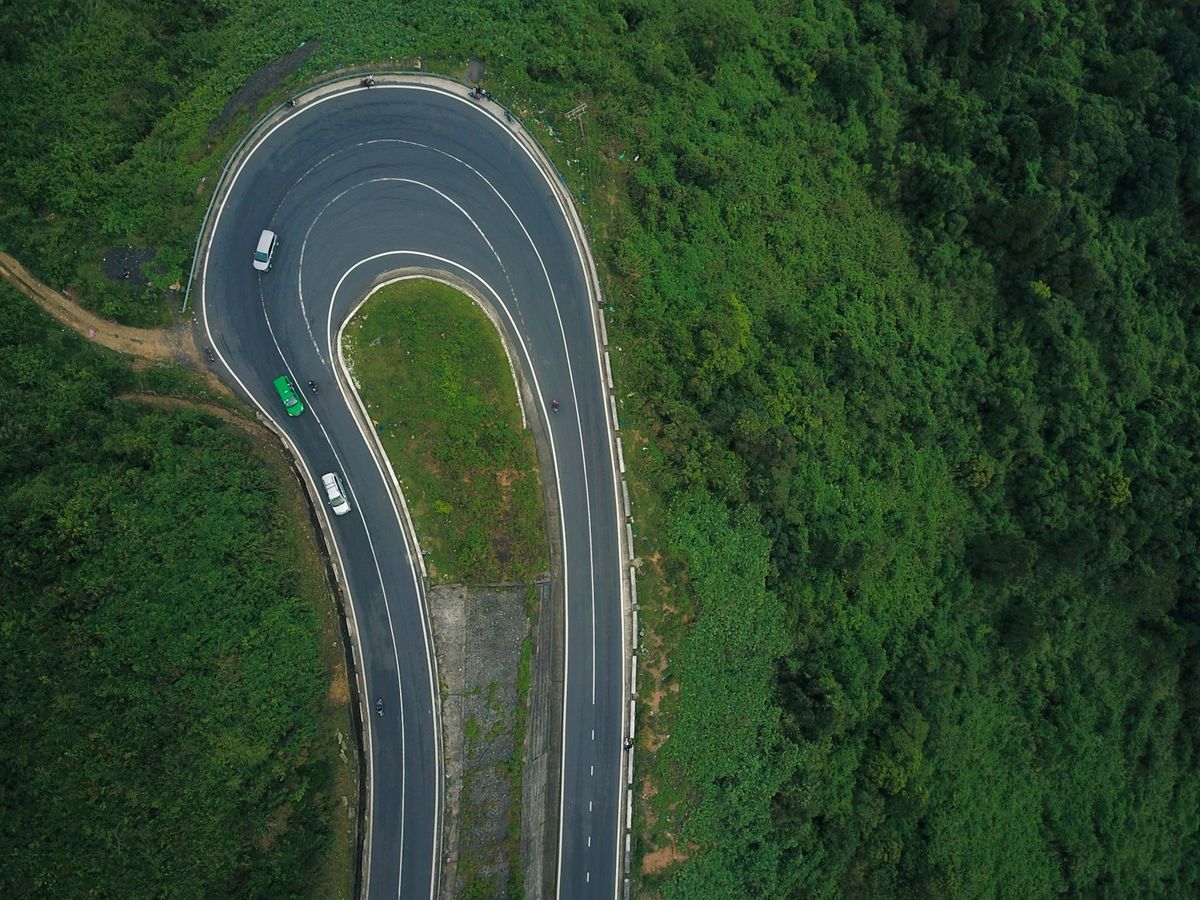 Aerial view of vehicles on a winding mountain pass road in Vietnam
