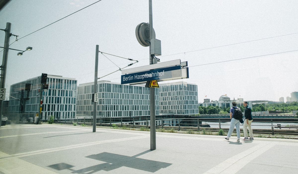 Travellers on a Berlin station platform by modern glass buildings