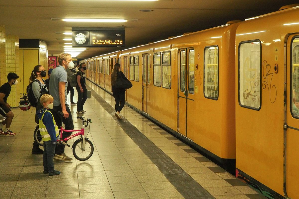 Group of people standing next to a yellow Berlin U-Bahn train