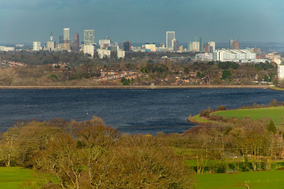 The Birmingham skyline seen across water and green hills