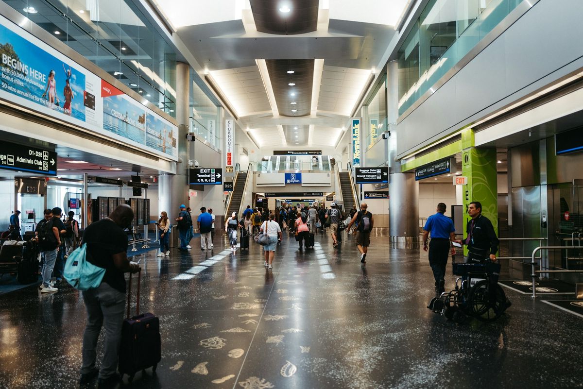 Travellers walking through a busy airport concourse terminal