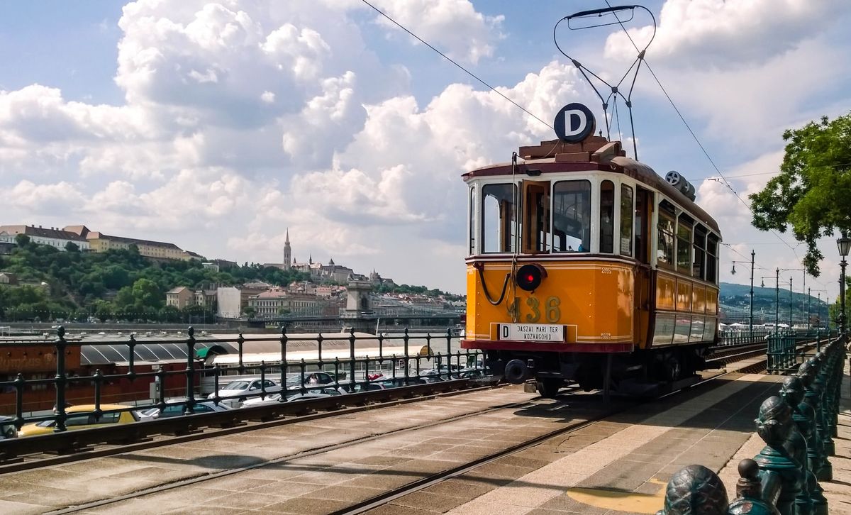 Yellow Budapest tram on bridge under blue sky