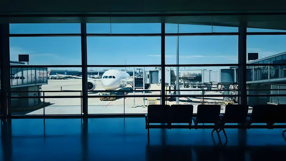 Airplane visible through airport terminal window at gate