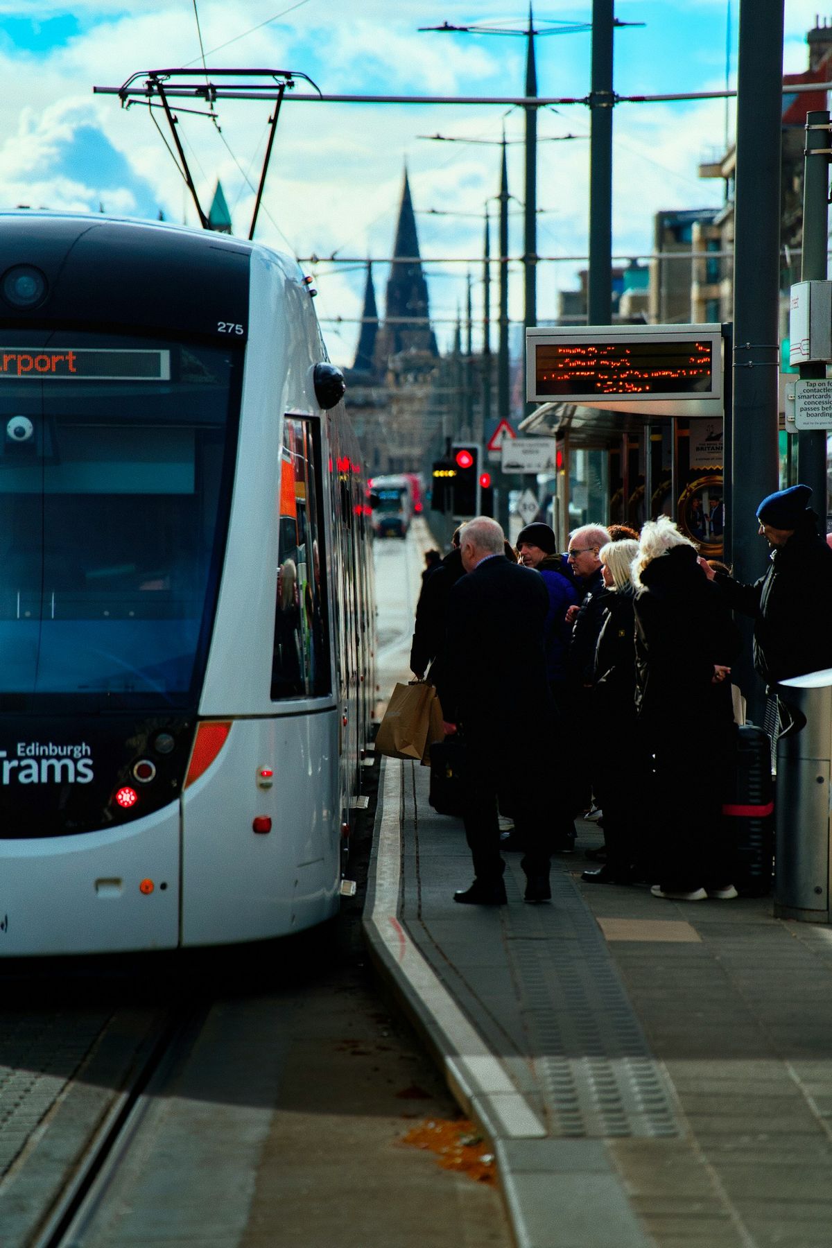 People waiting at Edinburgh tram stop with the castle in view