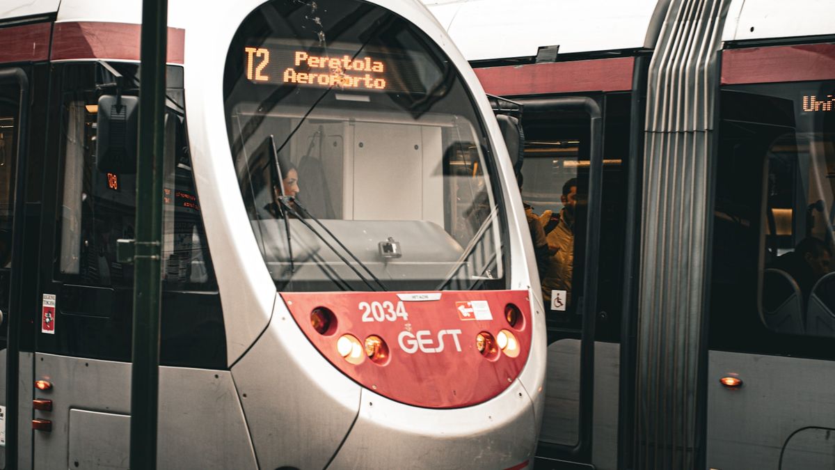 Silver and red tram travelling down train tracks in Florence, Italy