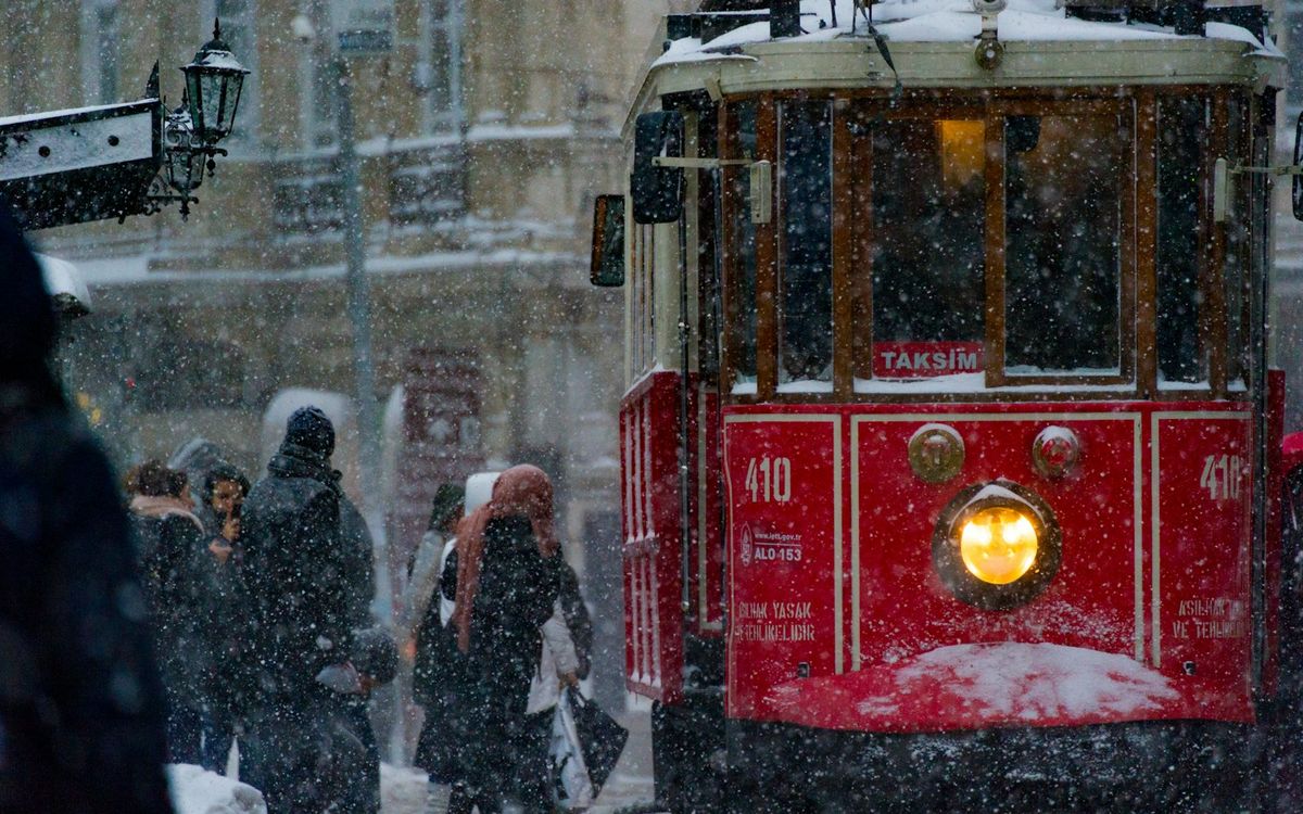 Pedestrians walking near a red tram in Istanbul