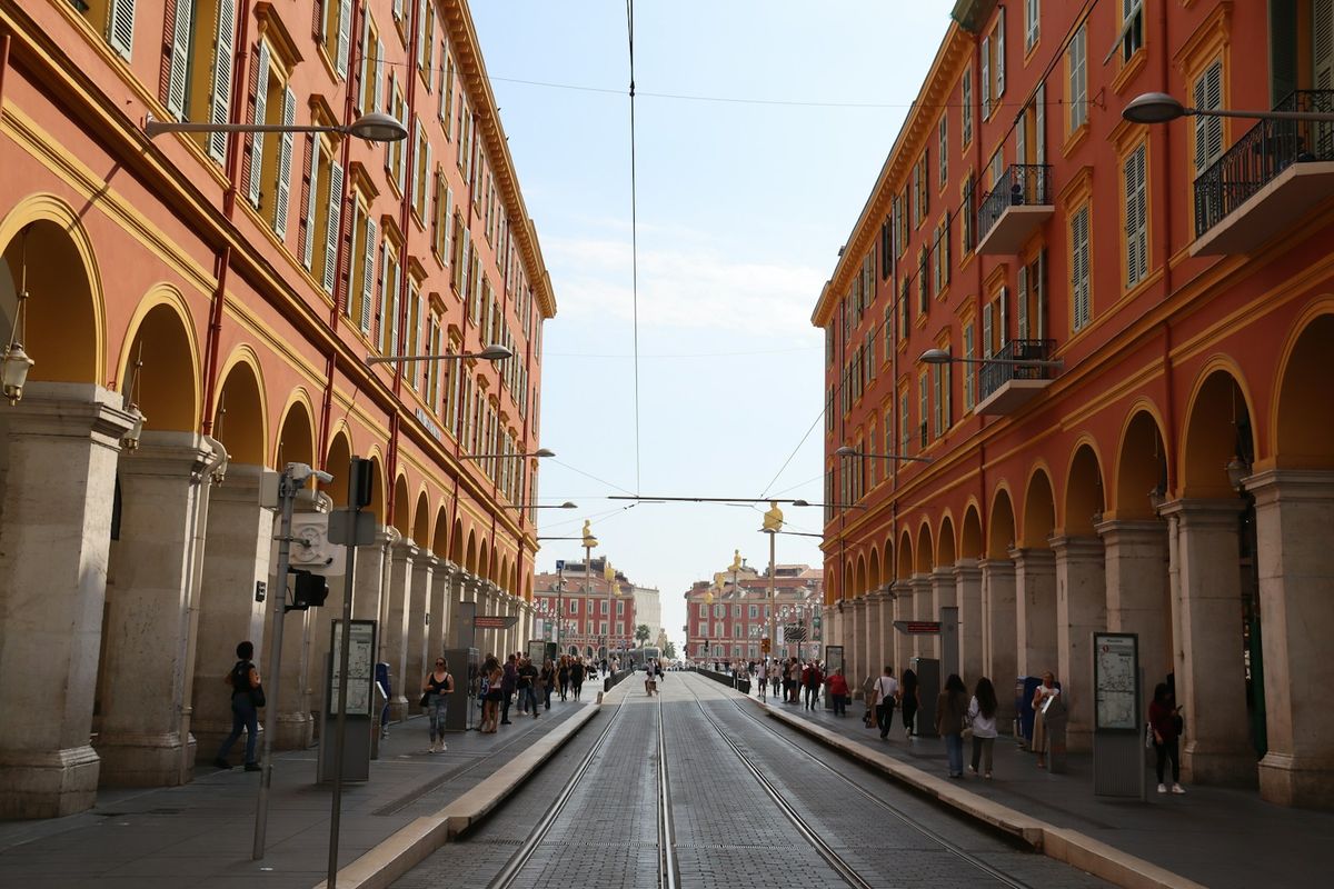 Orange buildings lining a wide street with tram tracks in Nice