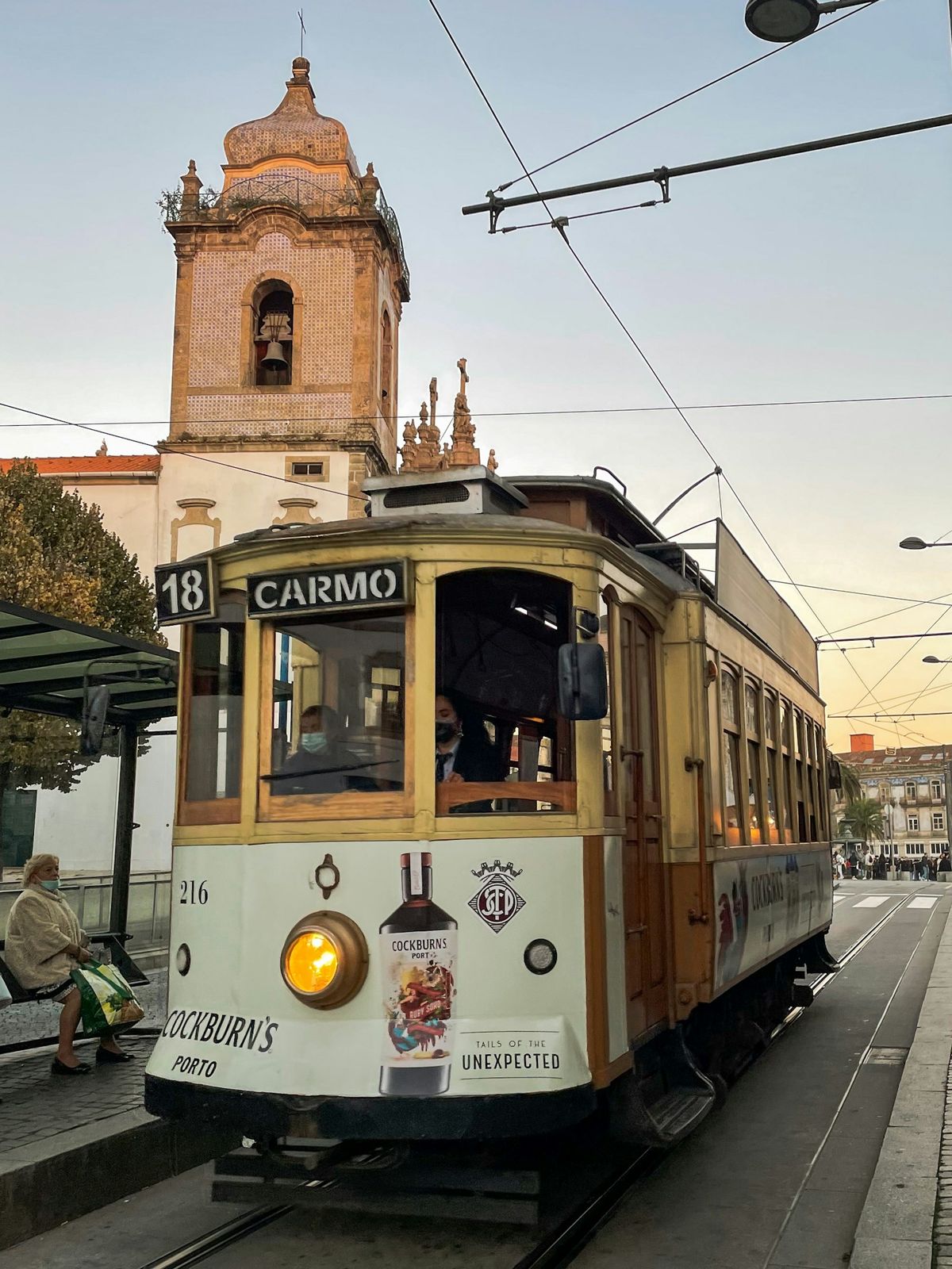 Porto tram on city street with historic clock tower