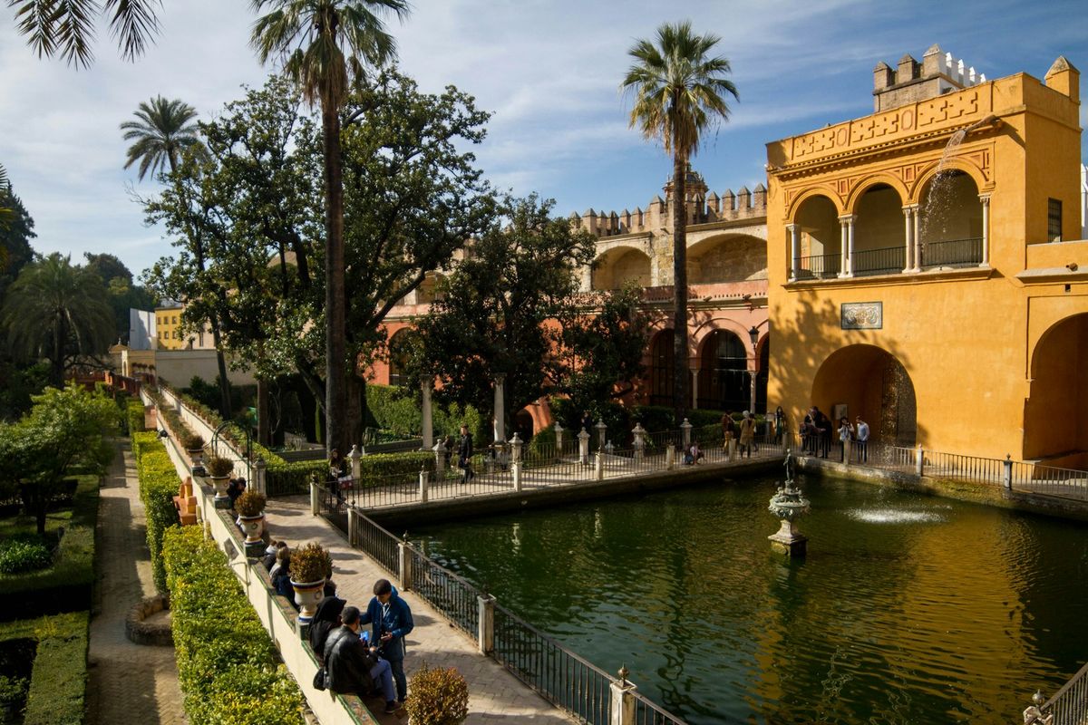 Ornate Alcazar palace courtyard with reflecting pool in Seville