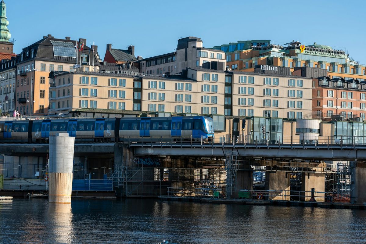 Stockholm Tunnelbana train traveling over a bridge with city buildings