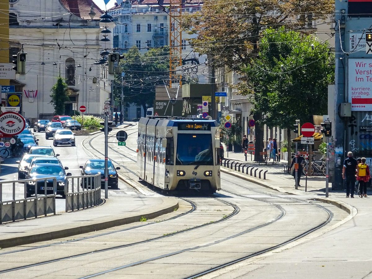 Red and white Vienna tram traveling down city street
