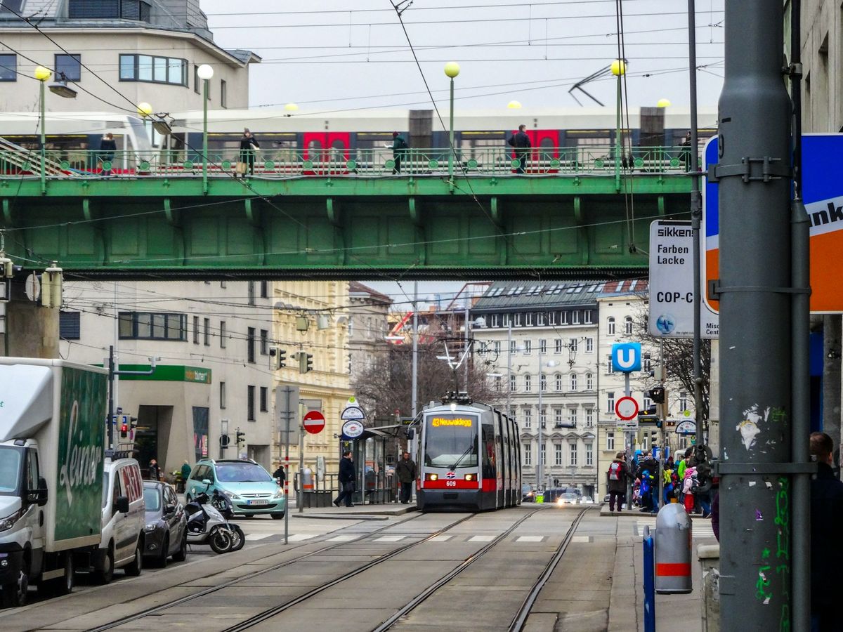 A tram and train passing through a Vienna city street