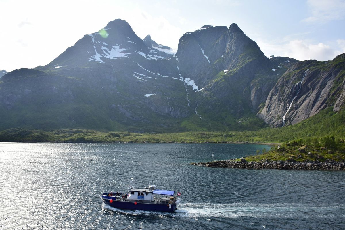 White and blue ferry vessel on Norwegian fjord near mountains