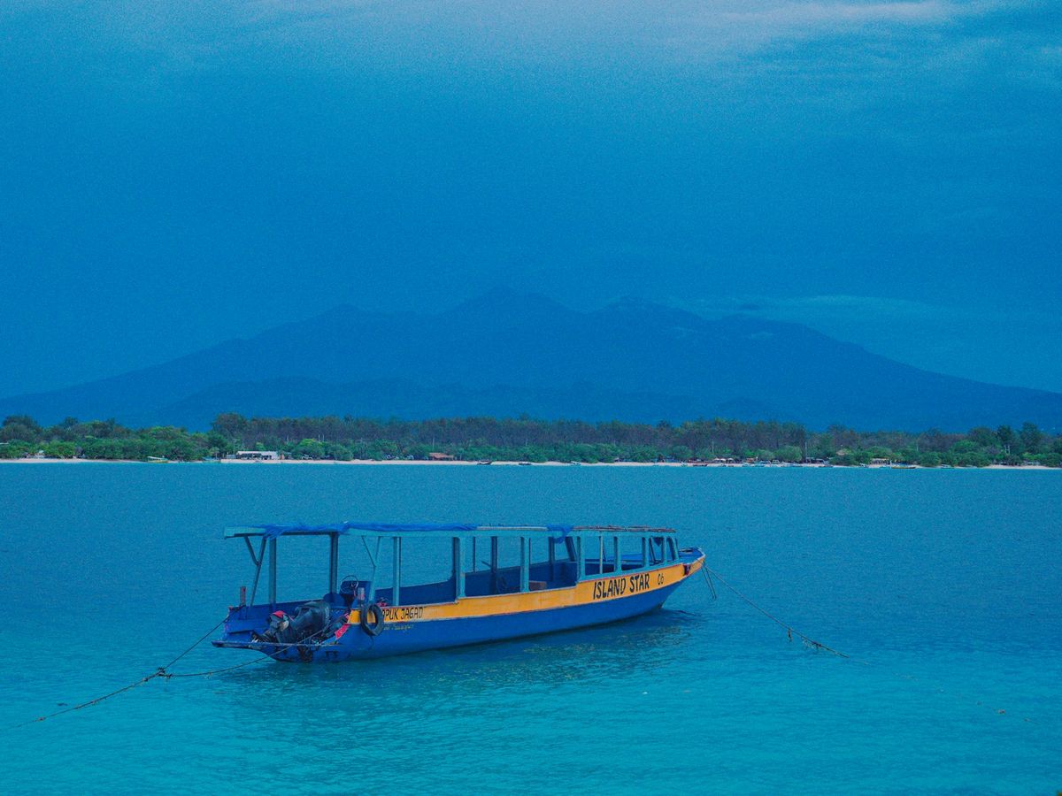 Traditional boat floating on clear blue water near tropical island in Indonesia
