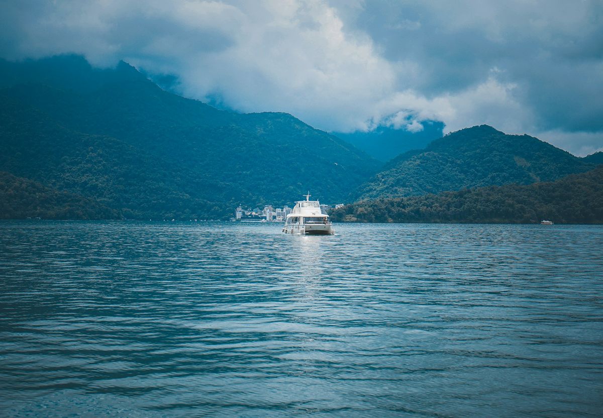 A ferry crossing the sea toward a green mountainous island in Taiwan