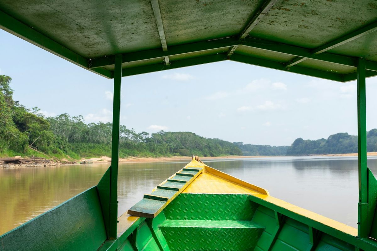 Boat travelling down a river through the Amazon rainforest