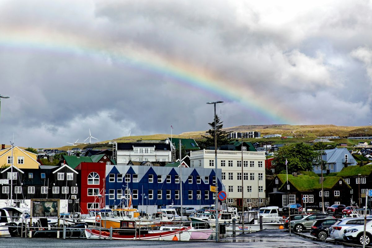 Colorful harbor buildings in Torshavn with rainbow over the water