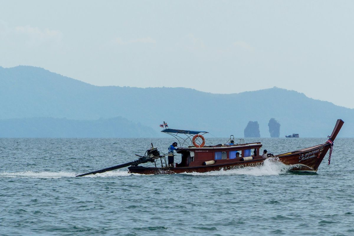 Longtail boat speeding across turquoise Thai island waters