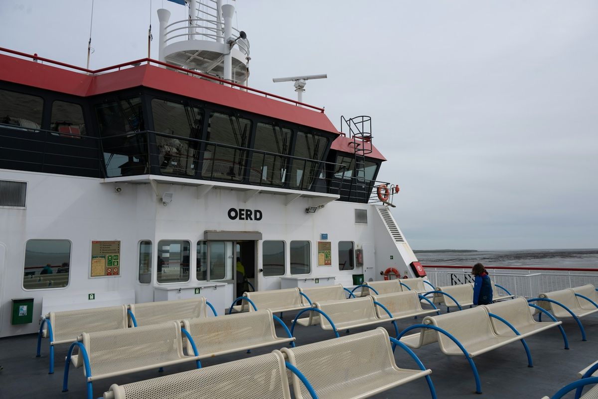 Ferry deck with rows of empty passenger benches overlooking the sea