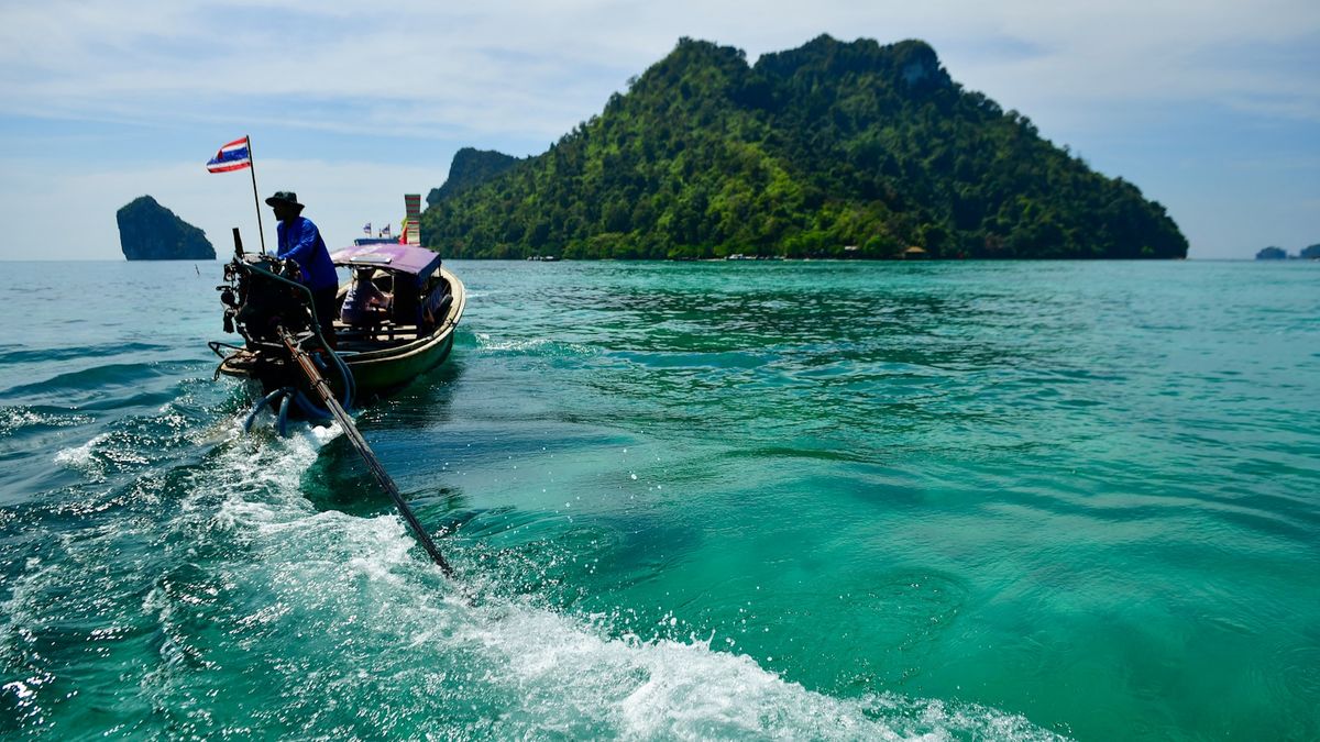 Longtail boat sailing towards a tropical island off Krabi