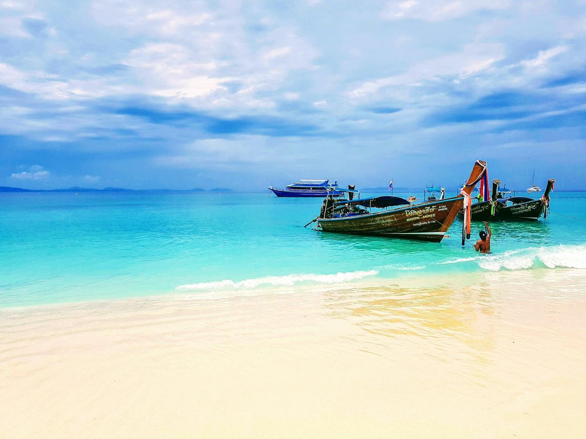 Traditional wooden boats on white sand beach in Thailand