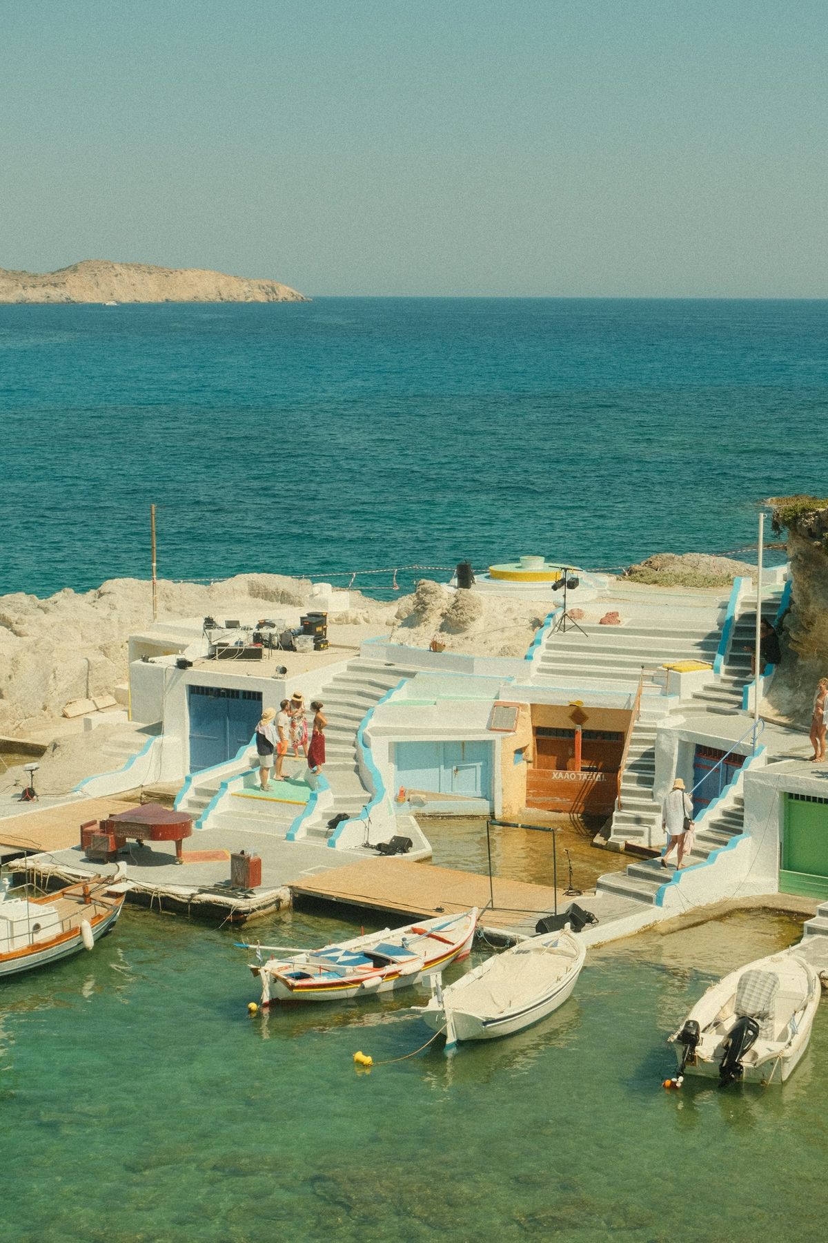 Boats in a small Greek harbour with white buildings along the shore
