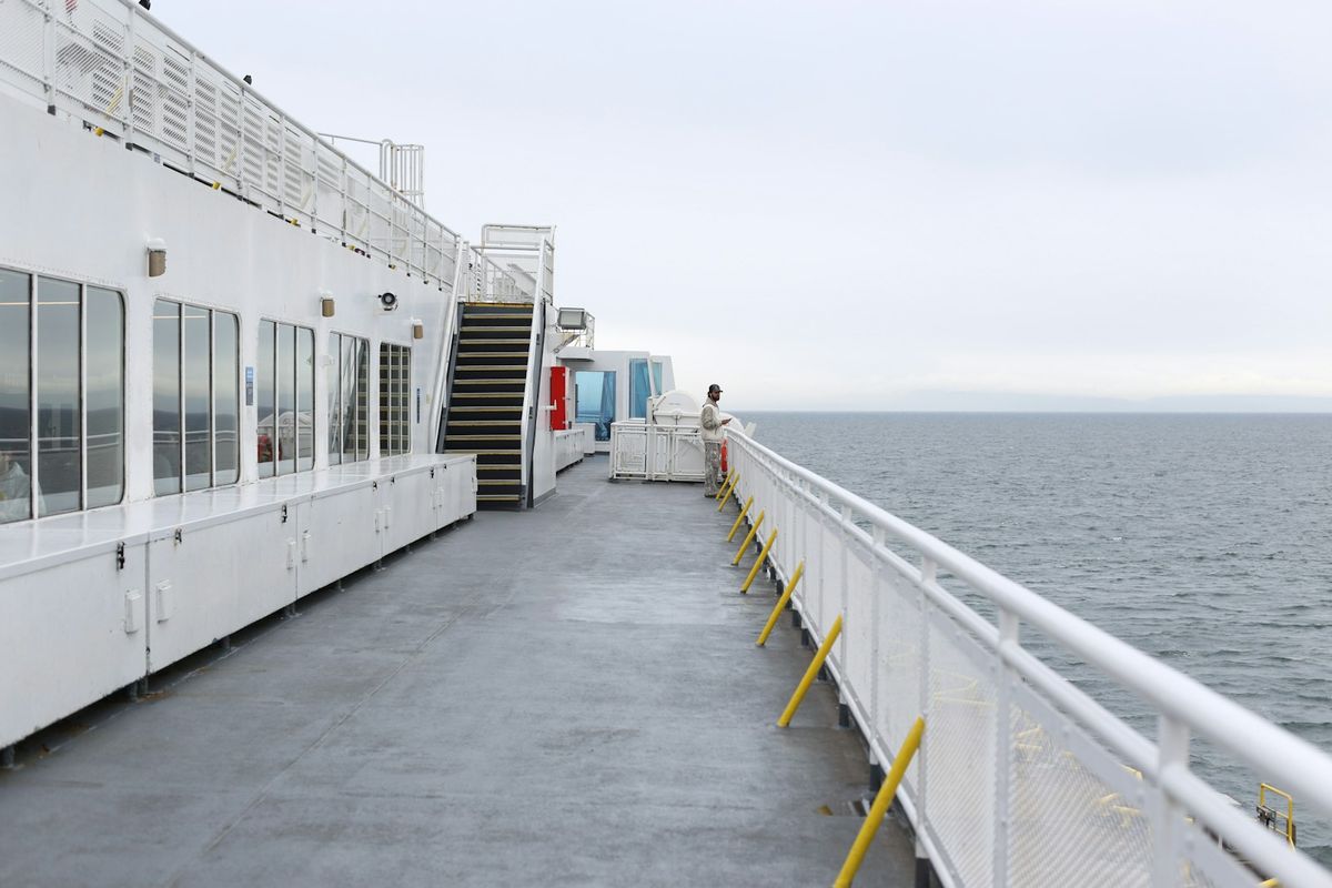 Passenger relaxing on a ferry deck overlooking the ocean