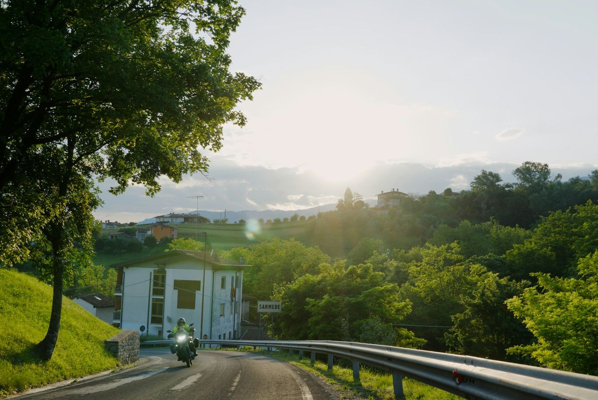 Motorcycle on a winding road through green European hills at sunset