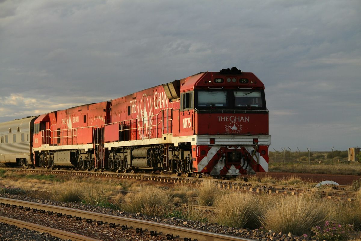 Red and white train on Australian railway tracks in the outback